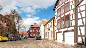 A cobblestone street lined with historic buildings, including a church and residential houses with traditional architecture.