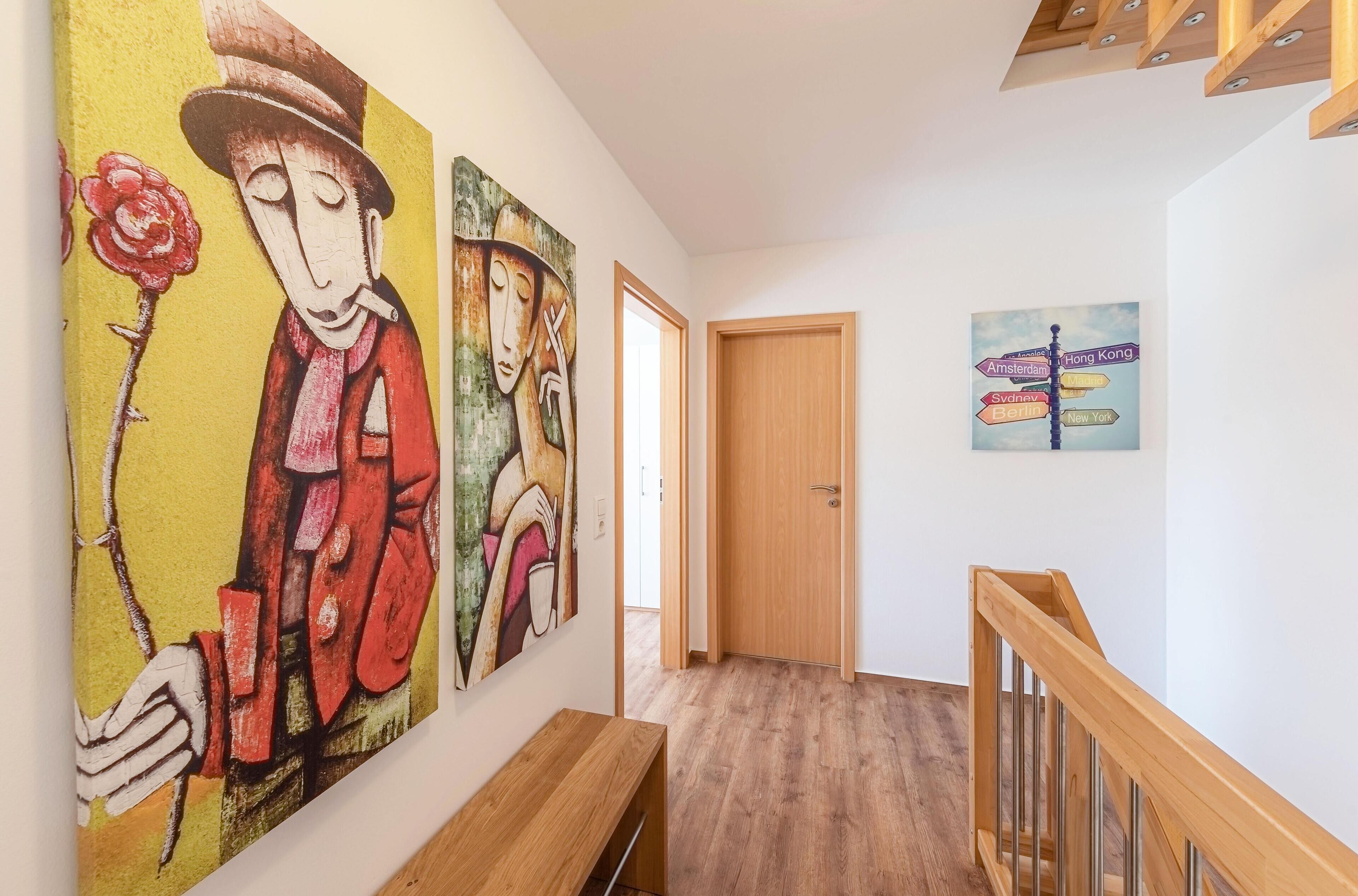 Ein Korridor mit Holzboden, einer Holzbank und zwei Bildern an der Wand.