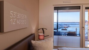Une chambre d’hôtel dotée d’une grande fenêtre donnant sur un port de plaisance et des bateaux.