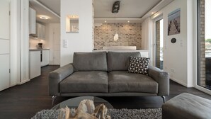 A modern living room with a grey sofa, a coffee table, and a fireplace. - Vacation apartment with water view on the 1st floor of the Hafenresidenz Waren (Waren (Müritz))