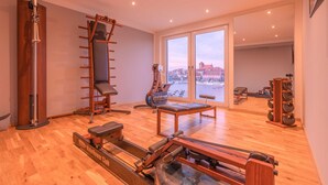 A spacious gym with a rowing machine, a pull-up bar, and a bench.