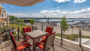 A balcony with a table and chairs, overlooking a marina with boats and a body of water.