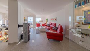 A modern living room with a red sofa, a white coffee table, and a glass cabinet with decorative items.