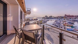 A balcony with a table and chairs overlooking a marina with boats. - 4-star apartment Sieglinde in the harbor residence. (Waren (Müritz))