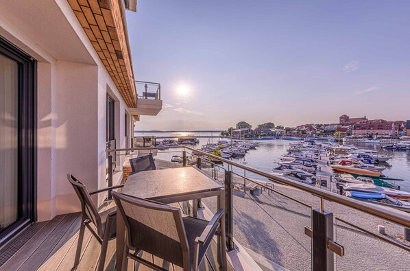 A balcony with a table and chairs overlooking a marina with boats.