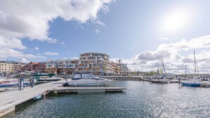 A marina with boats docked, a building with multiple balconies, and a clear sky with clouds. - 4-star apartment Sieglinde in the harbor residence. (Waren (Müritz))