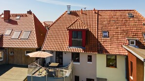 A residential building with a red-tiled roof, a balcony with a table and chairs, and a sign that reads "Haus Wasserbillich".