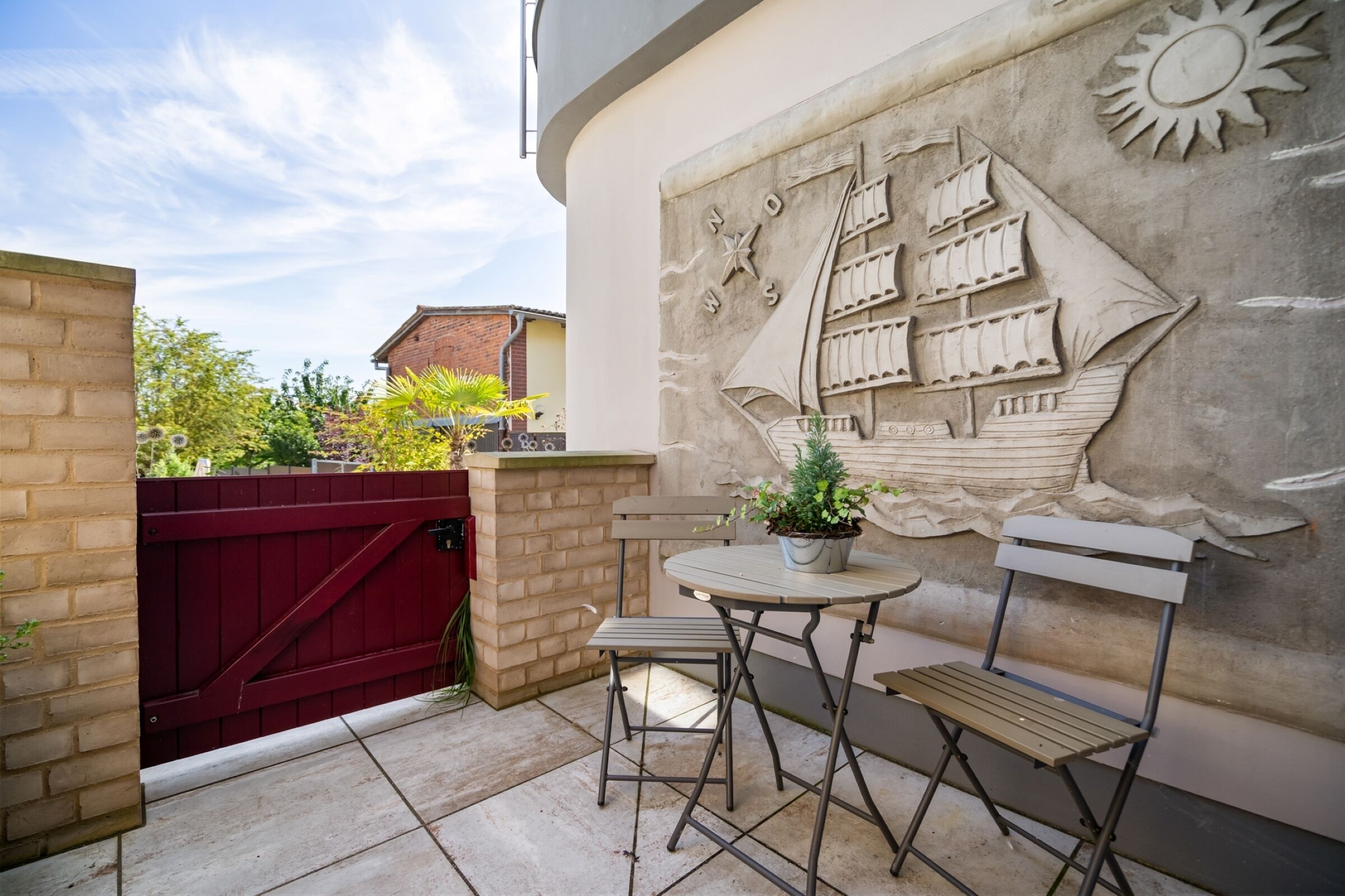 Eine Terrasse mit Tisch und Stühlen, einem Blumentopf und einer Wandmalerei.