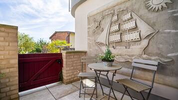 Eine Terrasse mit Tisch und Stühlen, einem Blumentopf und einer Wandmalerei.
