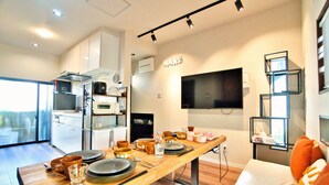 Una cucina moderna con mobili bianchi, un forno a microonde e un'area pranzo con un tavolo in legno apparecchiato per quattro persone.