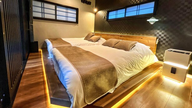 Una camera d'albergo moderna con un letto grande, un comodino, una TV a parete e una finestra con vista.