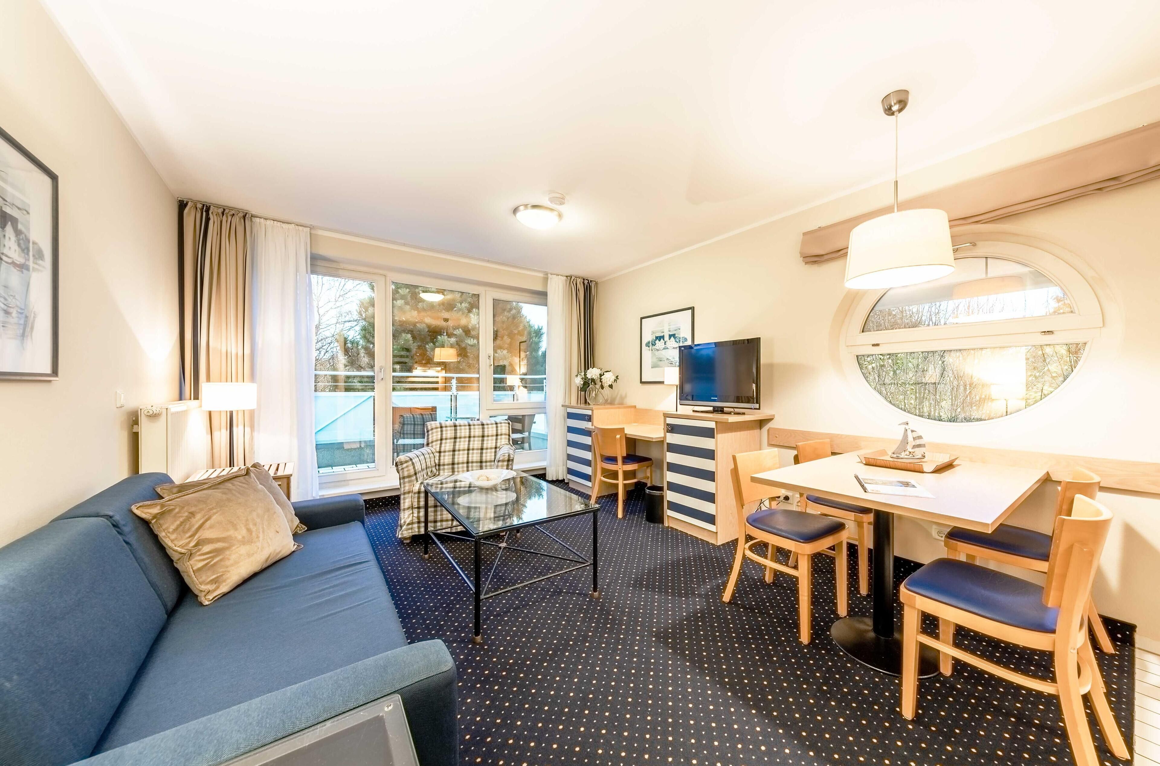 Une chambre d’hôtel de taille réduite, équipée d’un canapé, d’une petite table à manger et d’un téléviseur.