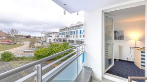 Un balcon donnant sur un ensemble d’immeubles, un petit espace extérieur avec des marches et une lampe dans la pièce.