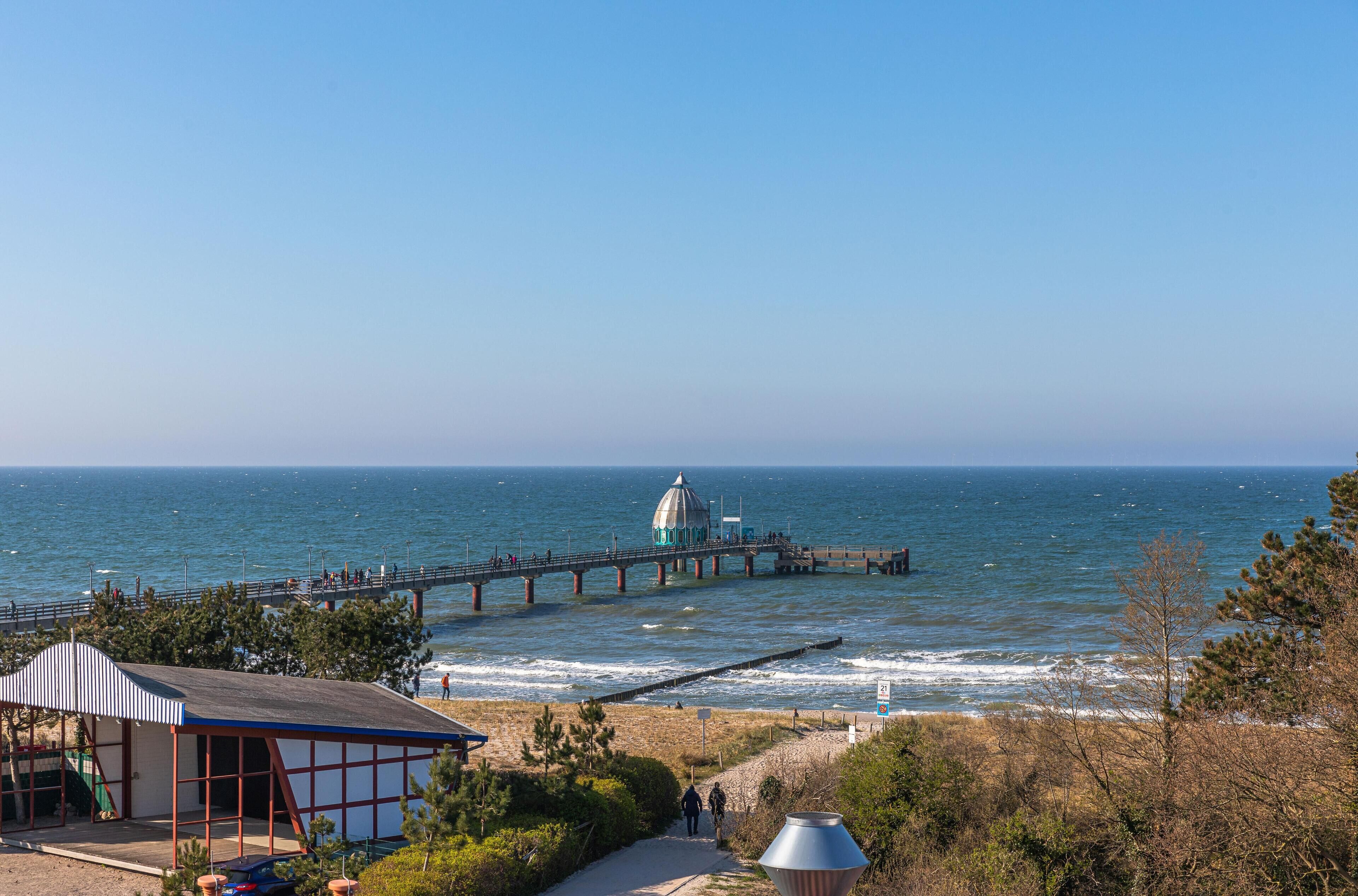 Une vue sur la côte, avec une jetée, une structure en forme de dôme et une plage dotée d’un espace de repos abrité.