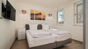 Ein modernes Schlafzimmer mit einem großen Bett, einem flachbildfernseher an der Wand und einem Fenster, das für natürliches Licht sorgt.