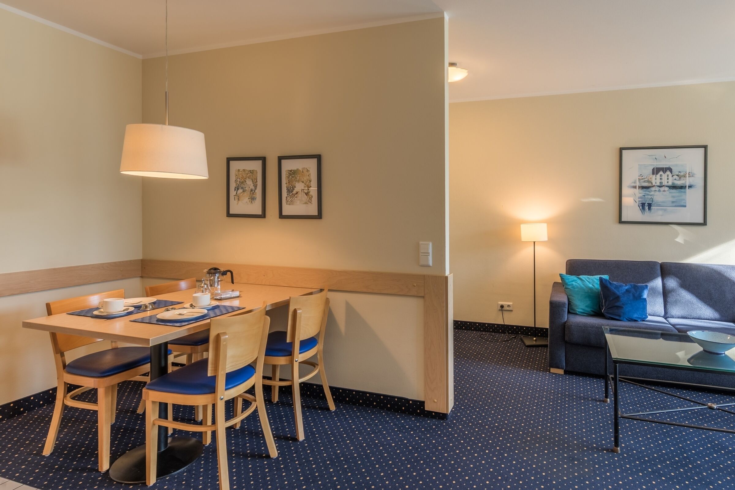 Hotellihuone, jossa on ruokailutila, sohva ja lamppu.