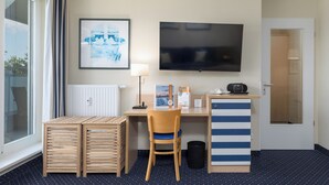 A hotel room with a desk, chair, TV, and a framed picture on the wall.