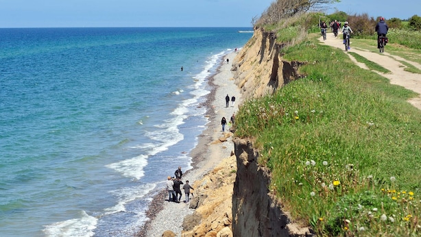 Un sentiero costiero con persone che camminano e vanno in bicicletta, con vista sul mare.