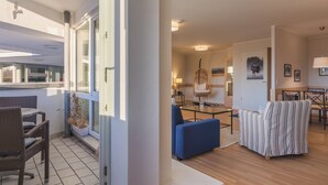 A spacious living area with a balcony, a dining area, and a seating arrangement. - "Kranichtanz" Vacation Rental with a Balcony and a View Toward the Dike (Zingst)