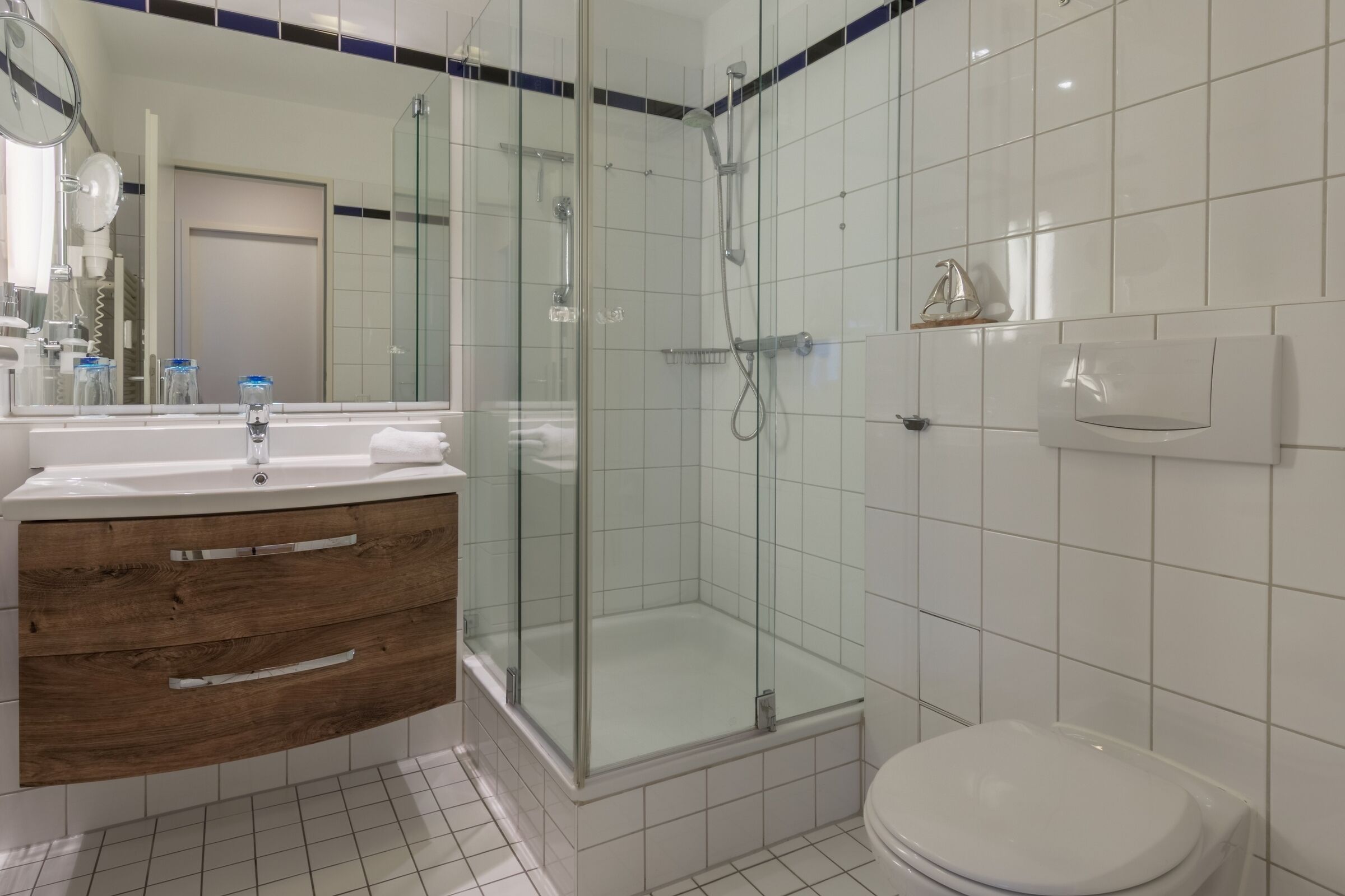 A modern bathroom with a glass-enclosed shower, a wooden vanity, and a white toilet.