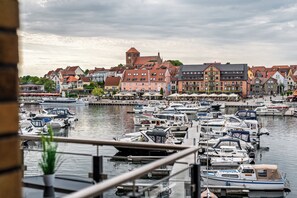 Ein Yachthafen mit vertäuten Booten, verschiedene Gebäude im Hintergrund und ein bewölkter Himmel.