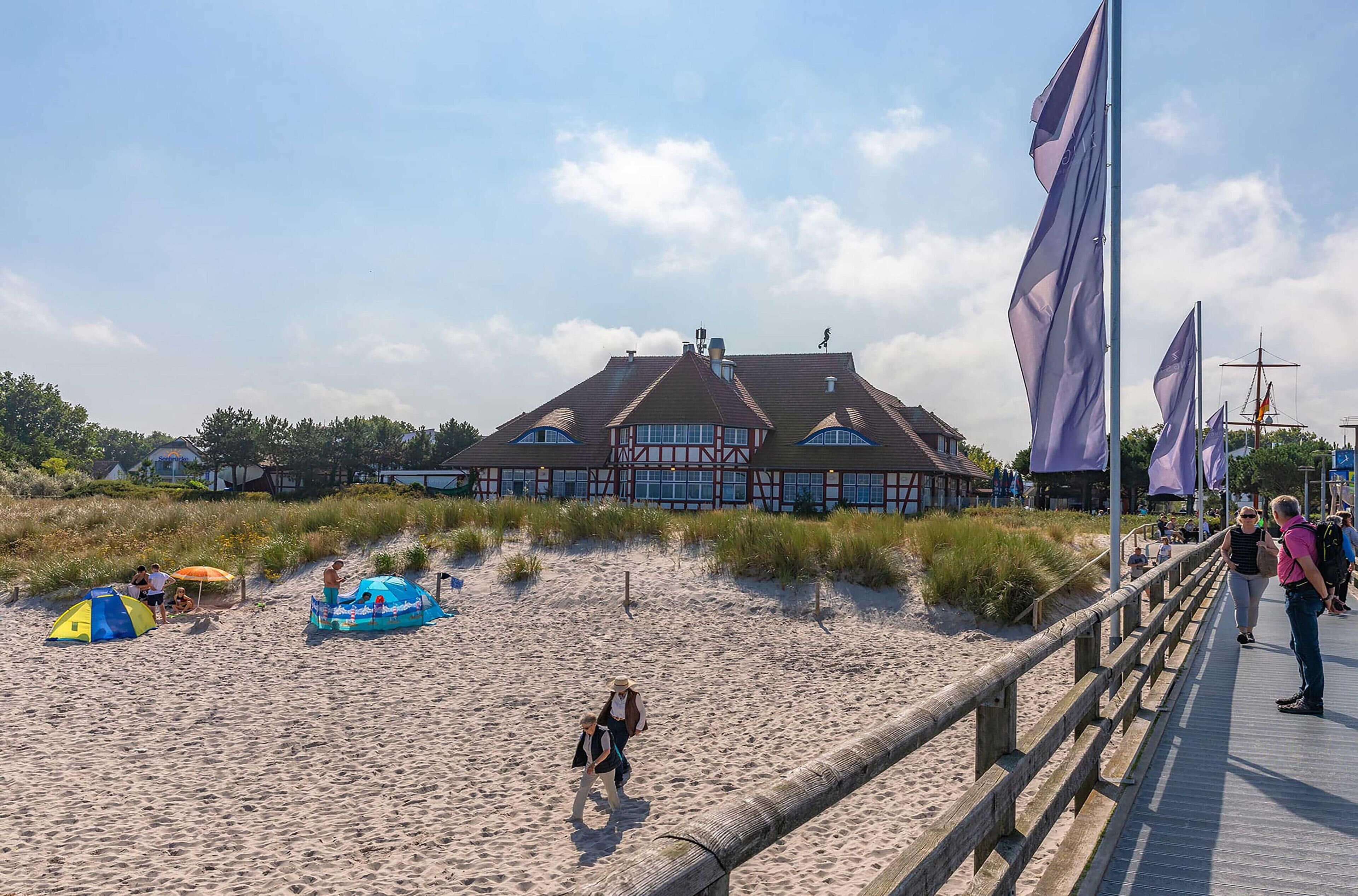Ein Gebäude direkt am Strand mit einem markanten Dach und einer Holzterrasse.