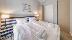 Habitación de hotel con una cama grande, dos mesitas de noche, una lámpara de pared, un cuadro enmarcado y un armario de madera.