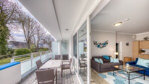 Un balcón con una mesa, sillas, un sofá y una zona de cocina.