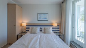 Una camera d'hotel con un letto grande, due lampade ai comodini, un quadro appeso al muro e una finestra con tende.