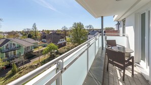 Un balcone con ringhiera in vetro che si affaccia su una zona residenziale.