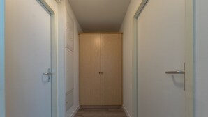 A narrow hallway with a wooden wardrobe and a door on the right.