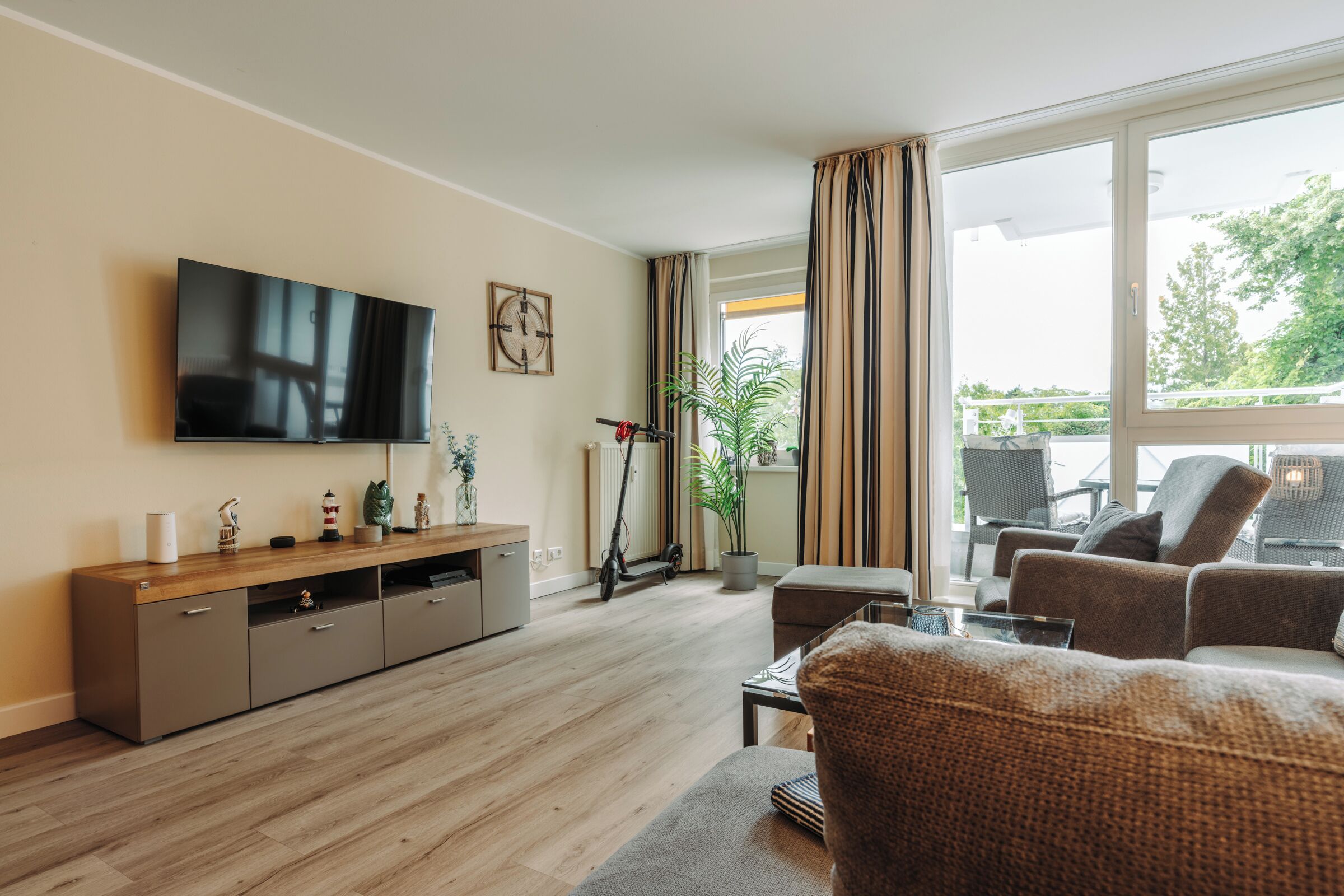 A modern living room with a flat-screen TV, a wooden entertainment unit, a sofa, and a dining area with a table and chairs.