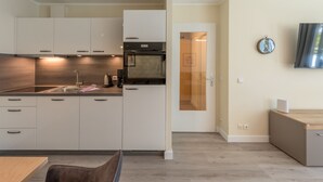 A modern kitchen with white cabinets, a built-in oven, and a wooden countertop.