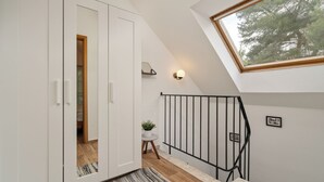 Un interior moderno con suelo de madera, un armario blanco y una pequeña mesa redonda con una planta.