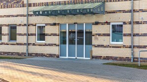 A building with a brick facade, a glass entrance, and a metal awning. - Sanddorn vacation apartment - pure relaxation just 200 meters from the Baltic Sea beach (Dierhagen)