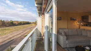 A balcony with a view of a road and trees, a sofa, and a lamp. - Sanddorn vacation apartment - pure relaxation just 200 meters from the Baltic Sea beach (Dierhagen)