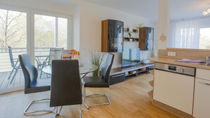 A modern kitchen with a dishwasher, a dining area with chairs, and a large window. - Sanddorn vacation apartment - pure relaxation just 200 meters from the Baltic Sea beach (Dierhagen)