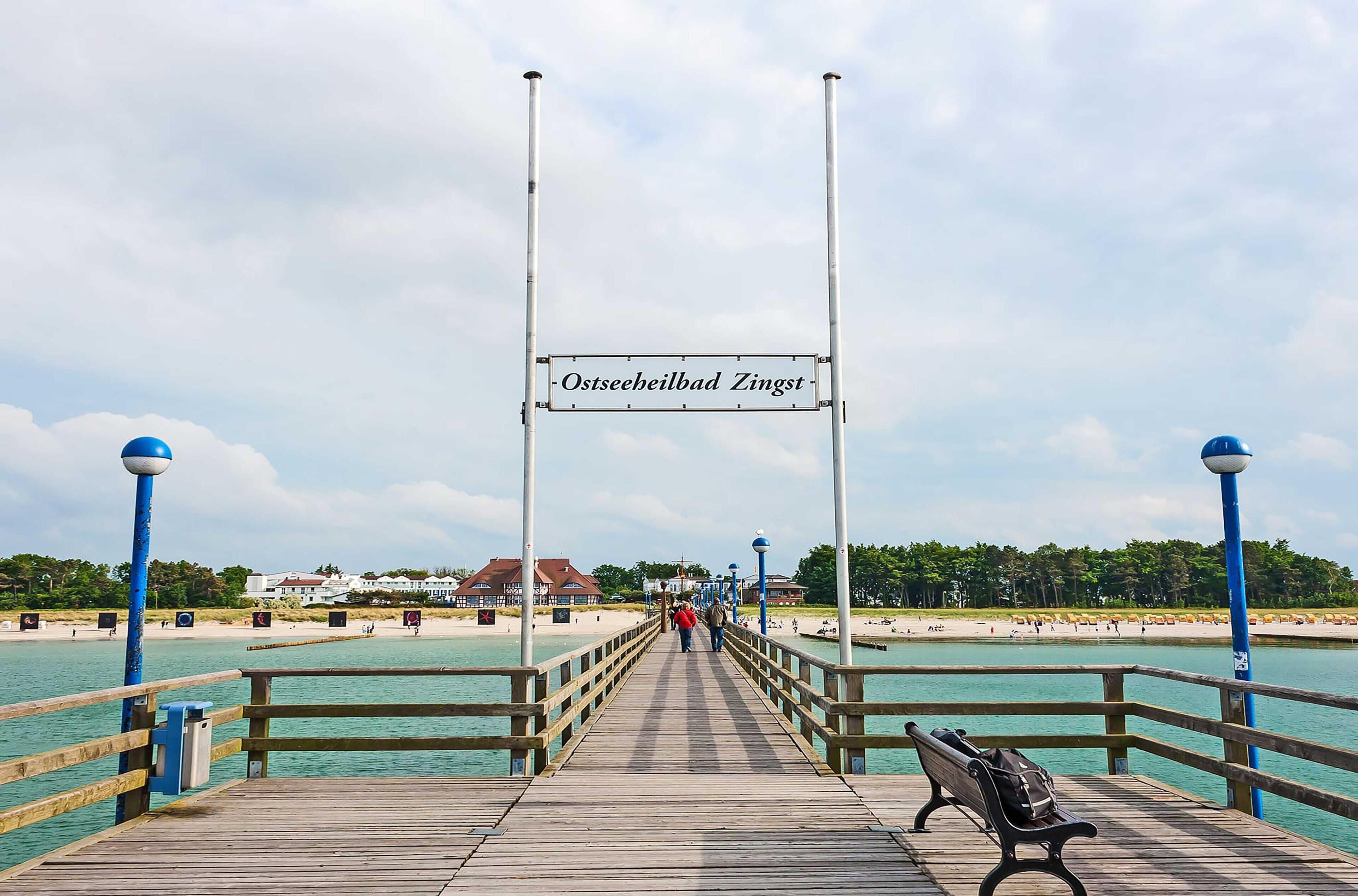 A pier with a sign reading "Ostseeheilbad Zingst" leading to a beach.
