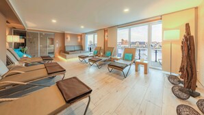 A modern hotel room with a balcony, lounge chairs, a flat-screen TV, and a city view. - Vacation apartment feel-good oasis with panoramic views and right next to the spa (Waren (Müritz))