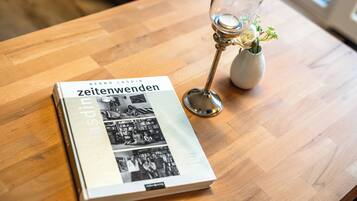 Een boek met de titel 'zeitenwenden' op een houten tafel, naast een glas met bloemdecoratie.