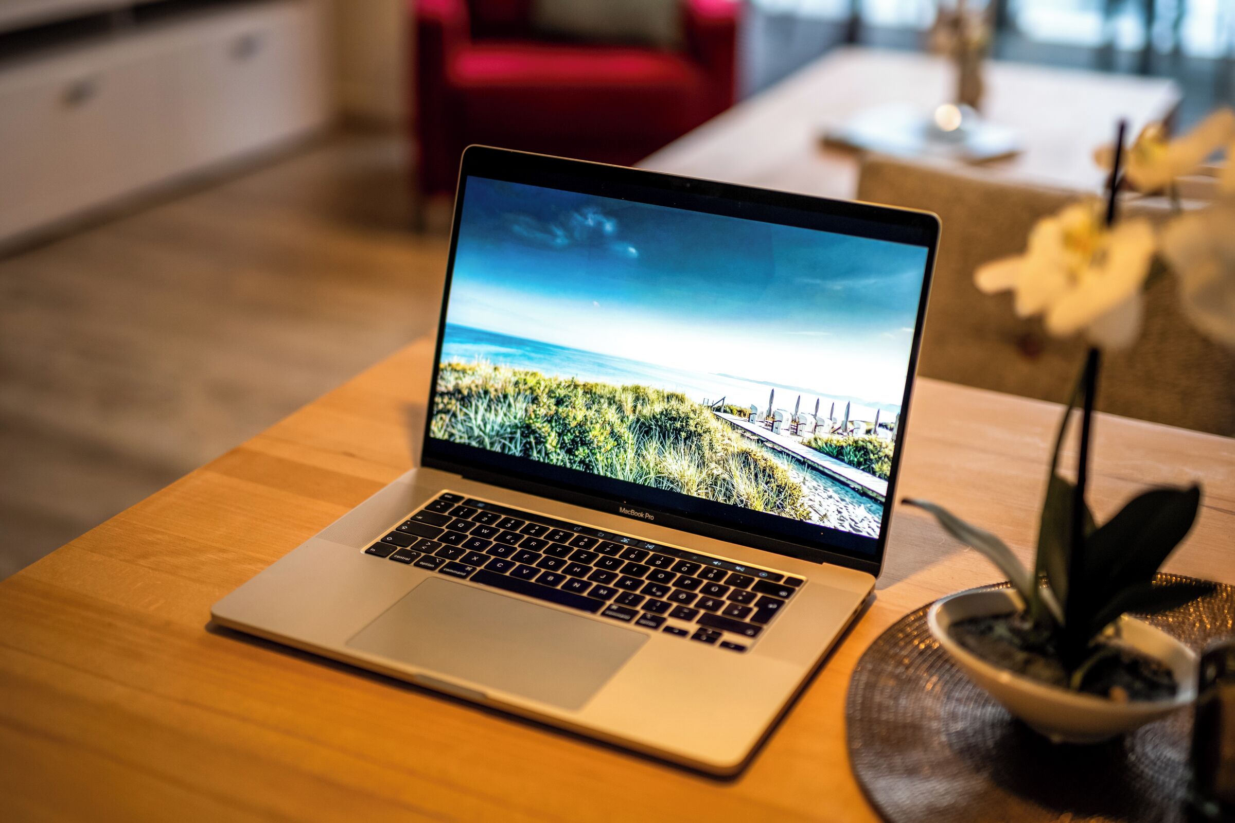 Un ordinateur portable est posé sur une table en bois, et l’écran affiche un paysage.
