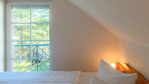 Quarto com cama, janela com vista para uma estrutura azul e abajur.