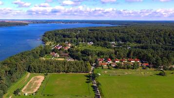 An aerial view of a lakeside community with houses, green fields, and a dock.