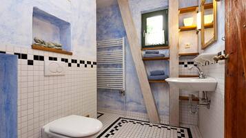 A bathroom with a white toilet, a sink, and a shower area.