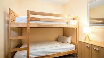 Una cama litera con estructura de madera, una mesita de noche con una lámpara y un espejo en la pared.