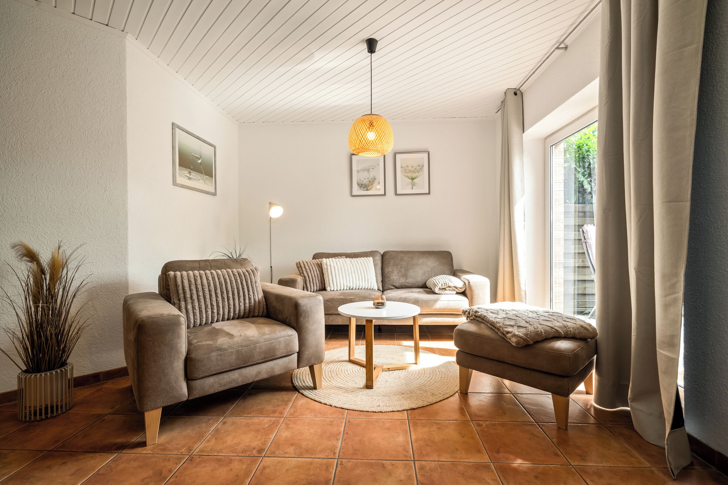 Un salon comprenant un canapé, un fauteuil, une table basse et un luminaire suspendu.