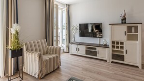 Una sala de estar moderna con un sofá a rayas, un televisor de pantalla plana, un mueble y una planta en maceta.