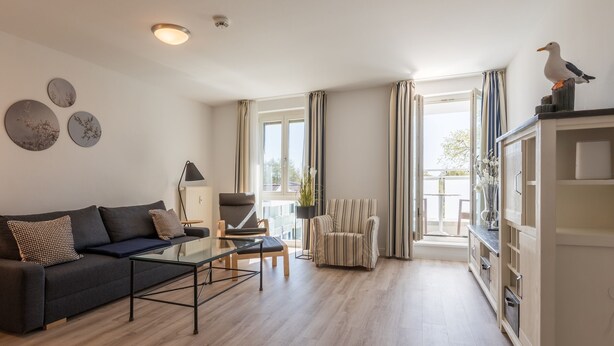 Una sala de estar moderna con un sofá, una mesa de centro, un sillón y una estantería.