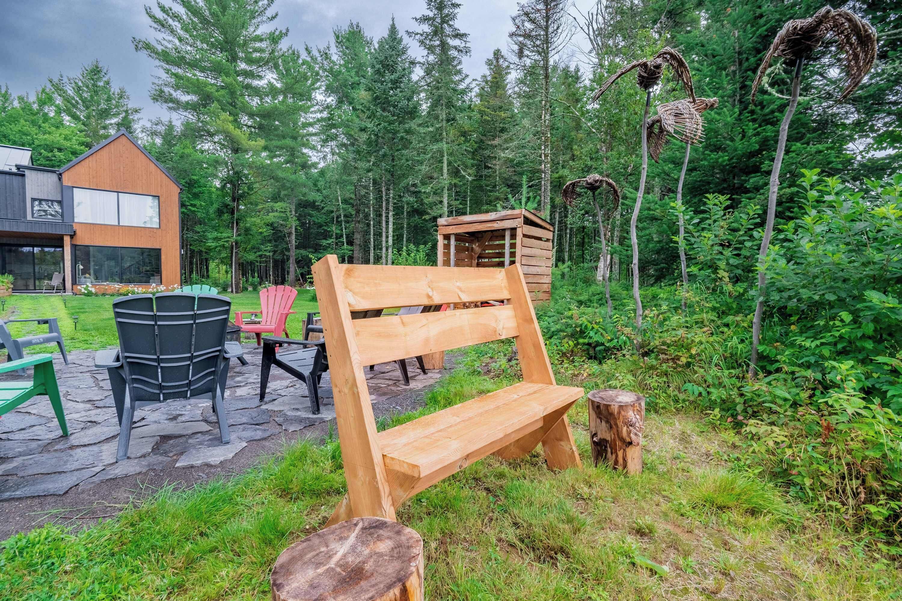 A wooden bench in a forested area with a modern building in the background.
