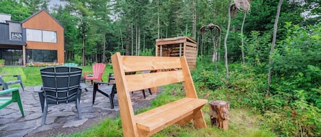 A wooden bench in a forested area with a modern building in the background.